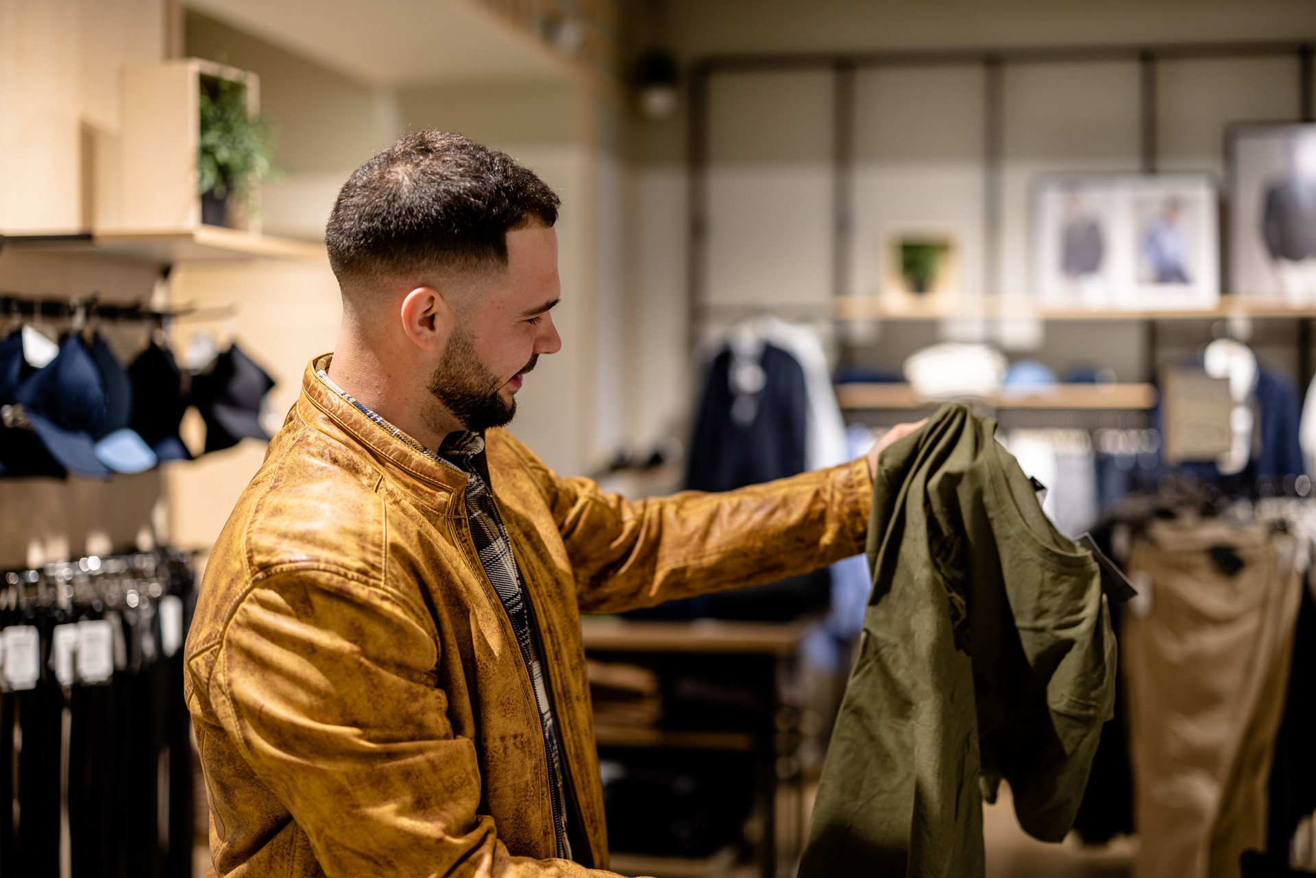 Young Man Takes Time Choosing Clothing at Store